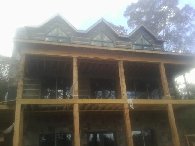 Dormers and porch framing on a large log home under construction — Roof Coating work by our crew in Pall Mall
