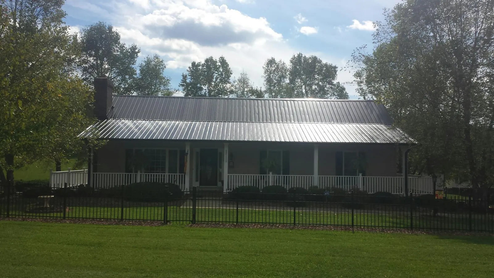 Gray metal roof on a brick ranch with a full width front porch — Gutter Guard Installation work by our crew in Pall Mall