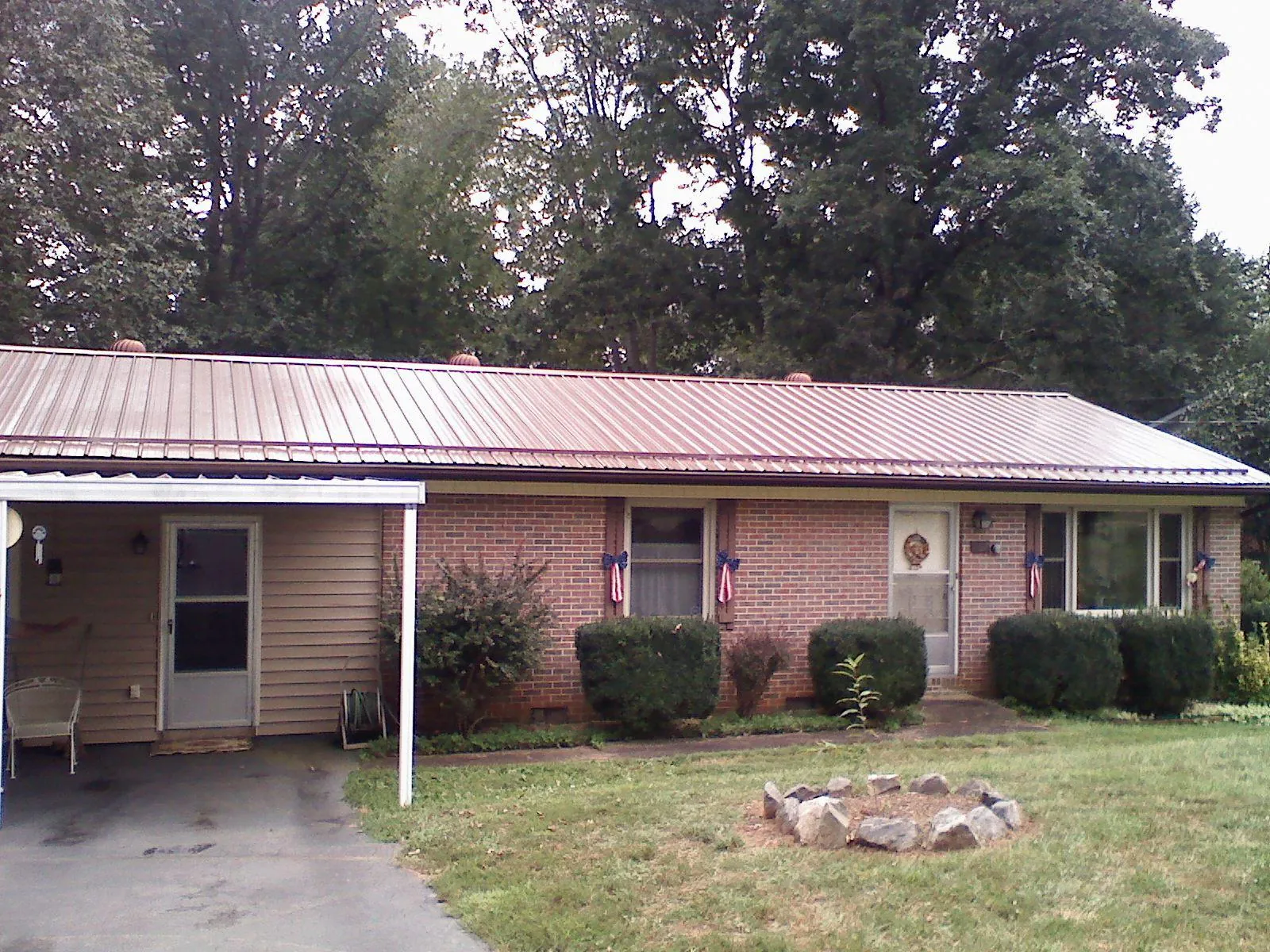 Bronze metal roof and carport on a brick ranch home — Roof Repair work by our crew in Pall Mall