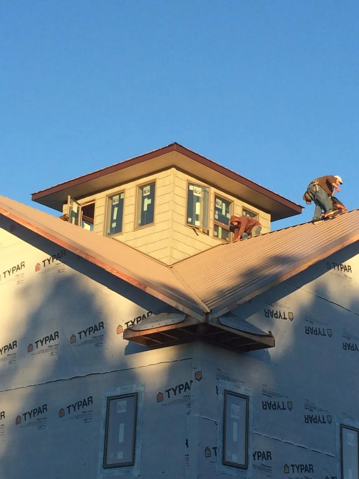 Roofers working around a rooftop cupola on a new metal roof at sunset — Roof Waterproofing in Pall Mall by Roofing Brothers